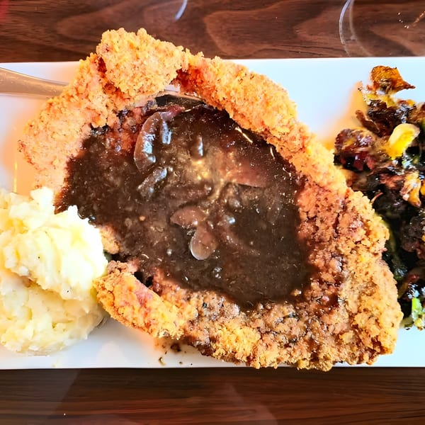 Liberty Tavern's chicken fried steak with gravy, mashed potatoes, and roasted vegetables on a white plate.